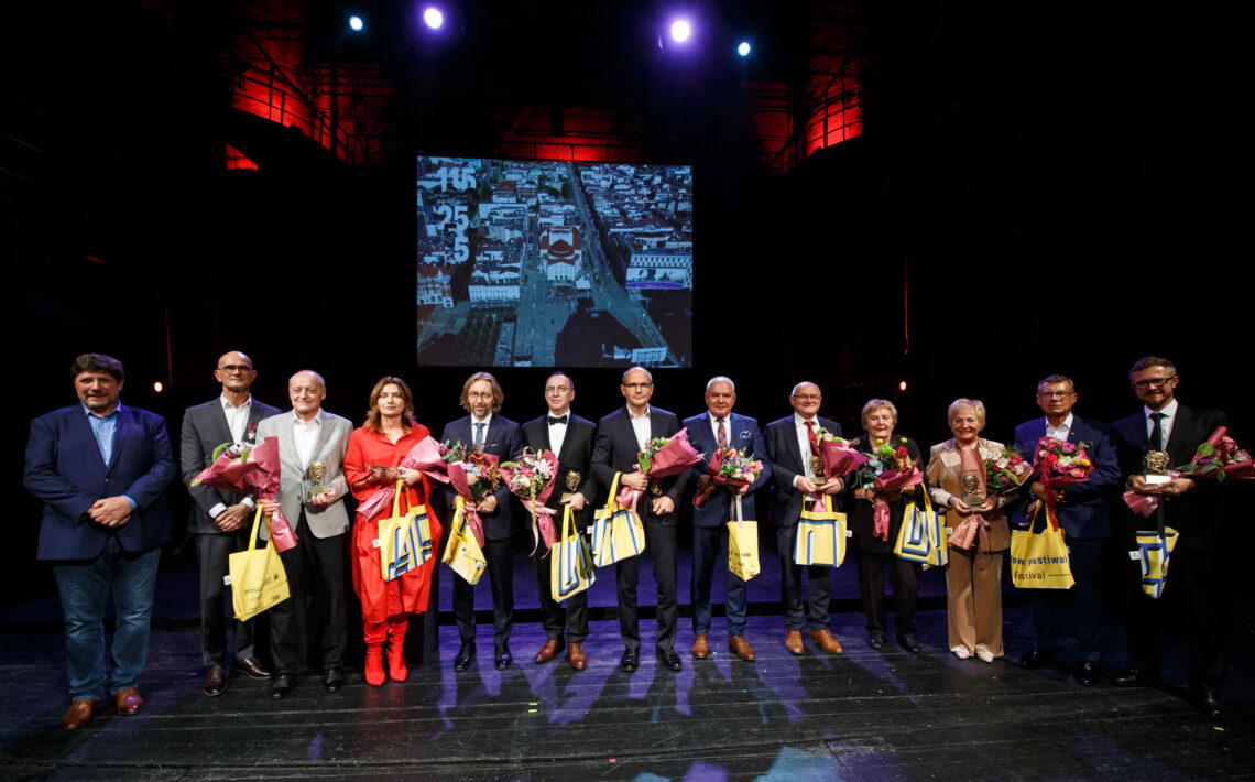 Członkowie Rady Mecenasów stojący w rzędzie z kwiatami, statuetkami oraz teatralnymi torbami w ręce, z lewej strony stoją Dyrektorzy Teatru