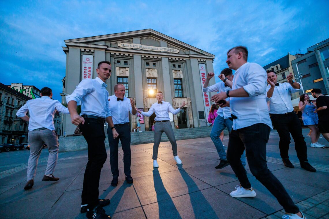 Mężczyźni tańczący na Rynku przed Teatrem Śląskim