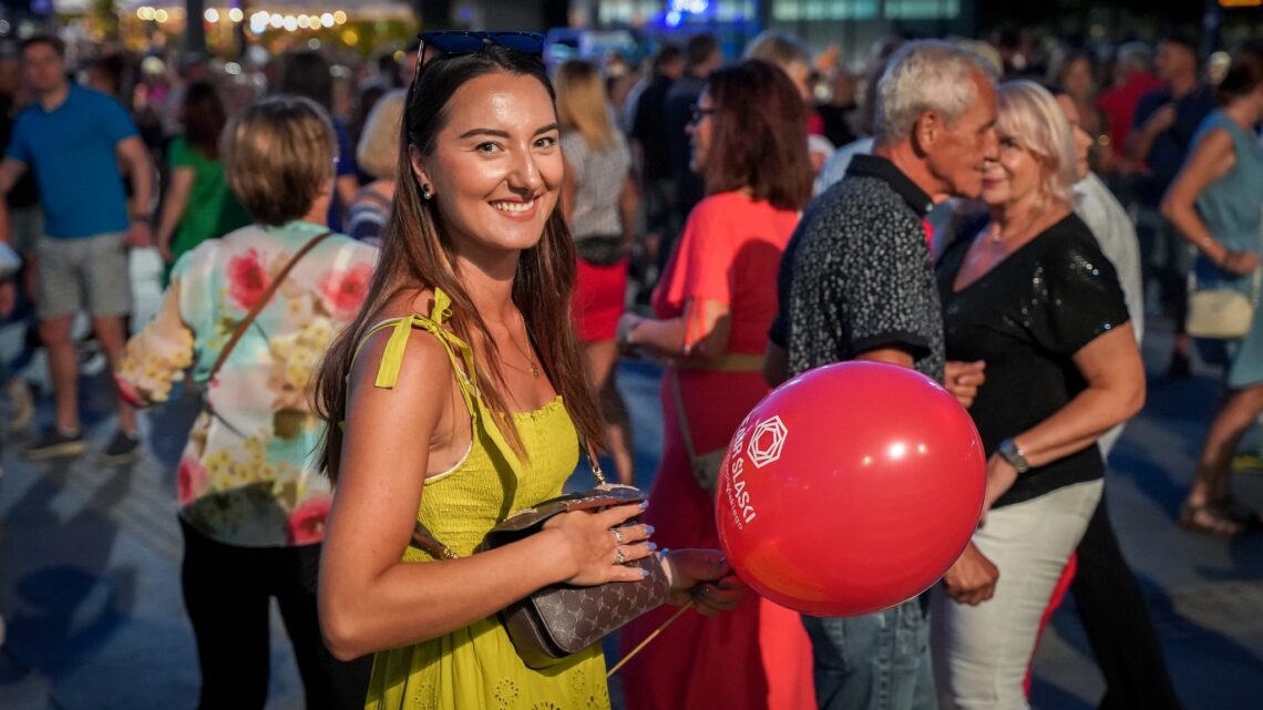 Dziewczyna w sukience trzymająca w ręce czerwony balonik z logo Teatru Śląskiego