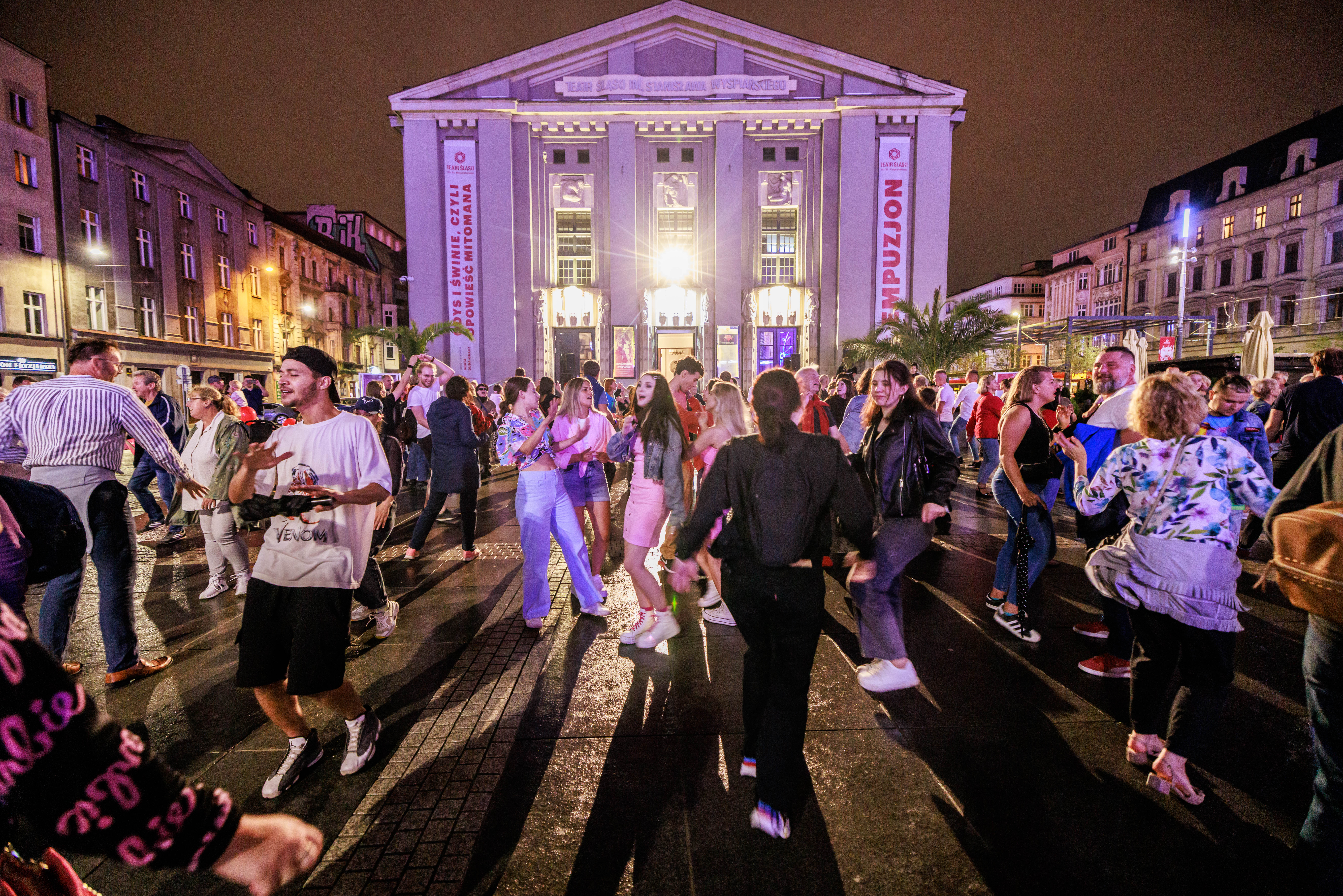 Grupa tańczących ludzi, w tle budynek Teatru Śląskiego
