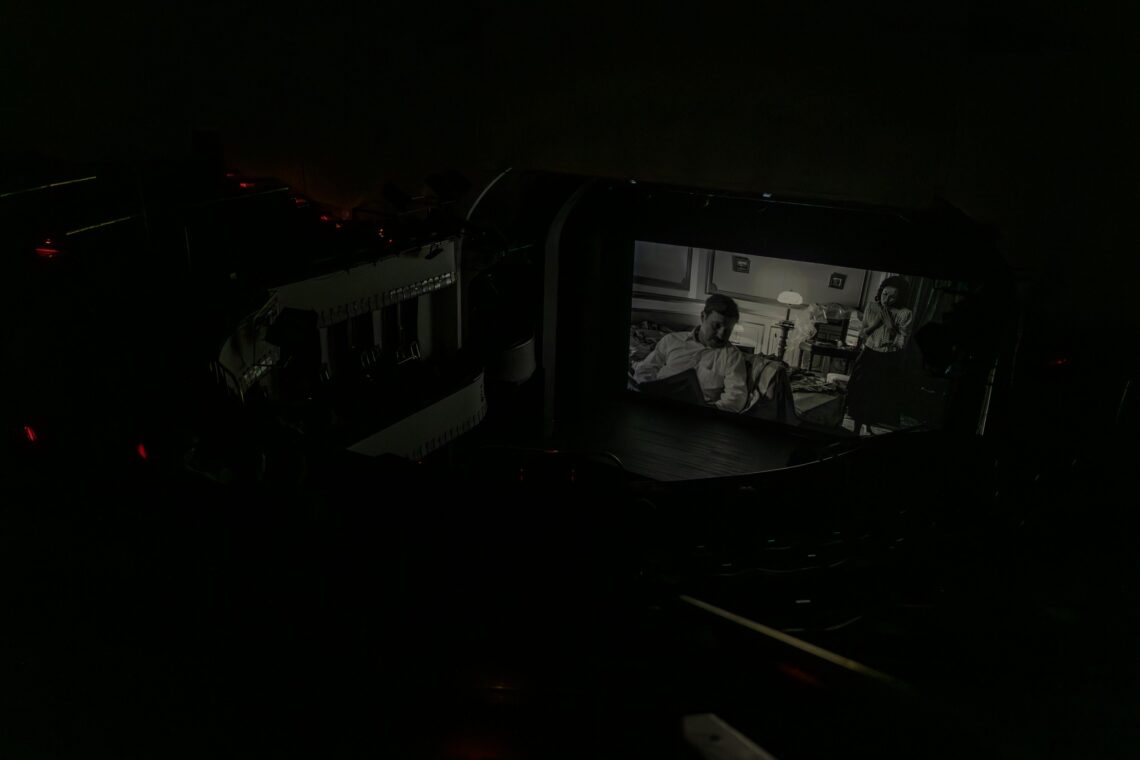 Na scenie Teatru na dużym ekranie wyświetlany jest czarno-biały film, widownia pogrążona jest w ciemności, ujęcie z góry