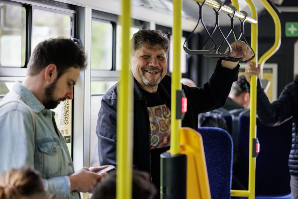 Dyrektor Robert Talarczyk stojący w autobusie, trzyma się za ręczny uchwyt wiszący