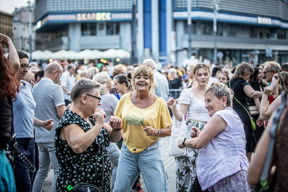 Kobiety w trakcie tańca, za nimi widoczne inne osoby