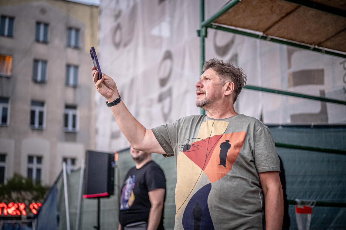 Dyrektor Robert Talarczyk w trakcie robienia zdjęcia, dłoń z telefonem ma wyciągniętą do góry i do przodu