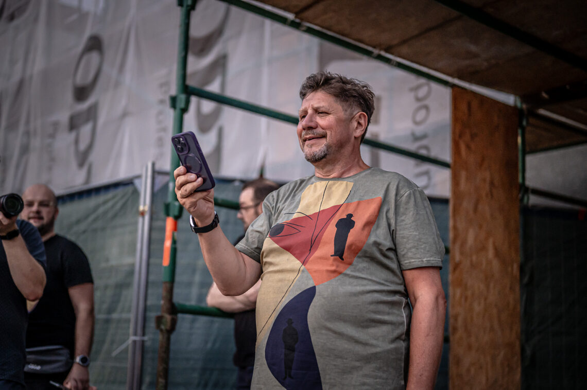 Dyrektor Robert Talarczyk stojący z telefonem w dłoni