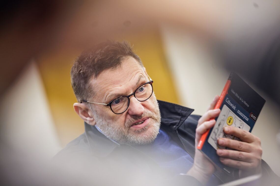 Profesor Zbigniew Kadłubek trzymający w dłoni książkę "Człowiek - maszyna", dłonią zasłania część okładki