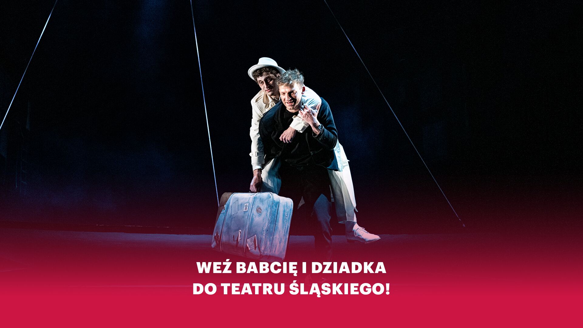 Grafika: w dole na czerwonym tle biały napis Weź babcię i dziadka do Teatru Śląskiego!, w tle mężczyzna ubrany na czarno niosący na plecach mężczyznę ubranego na biało z dużą walizką w prawej dłoni