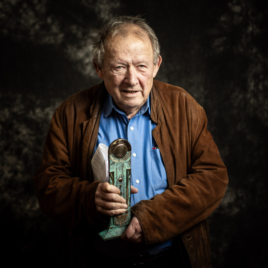 Zdjęcie portretowe Adama Michnika trzymającego w dłoniach statuetkę Nagrody