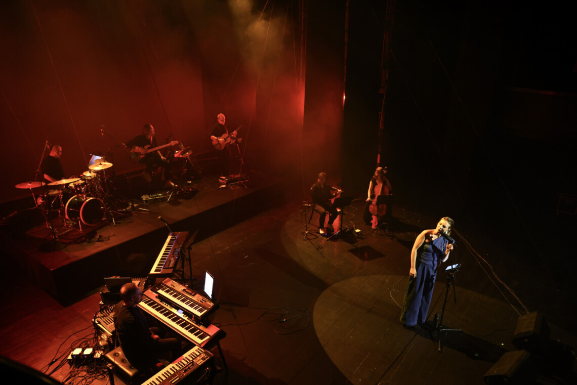 Piosenkarka i muzycy na scenie; ujęcie od góry, scena oświetlona na czerwono