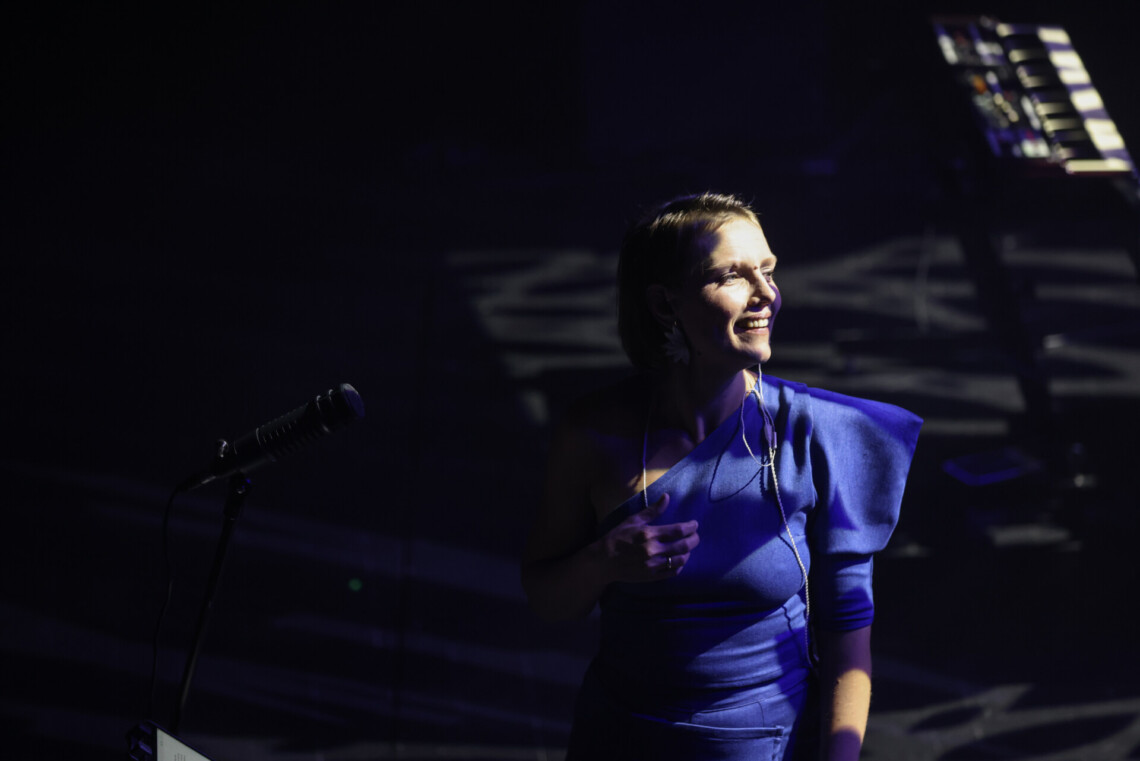 Piosenkarka patrząca w przeciwnym kierunku niż stojący przed nią mikrofon; przybliżenie