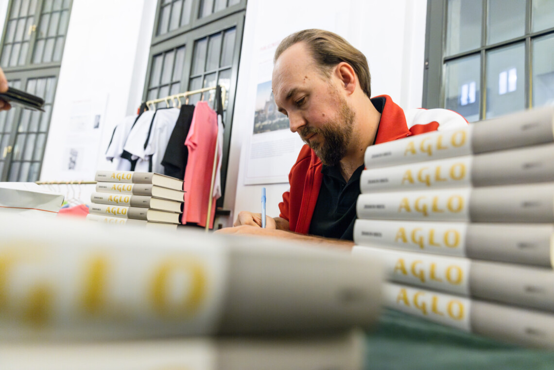 Zbigniew Rokita podpisujący swoją książkę, ujęcie od dołu zza książek