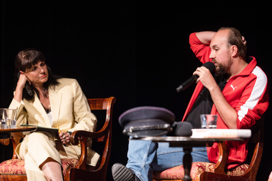 Anna Dudzińska oraz Zbigniew Rokita siedzą na krzesłach obok siebie, mężczyzna przemawia do mikrofonu