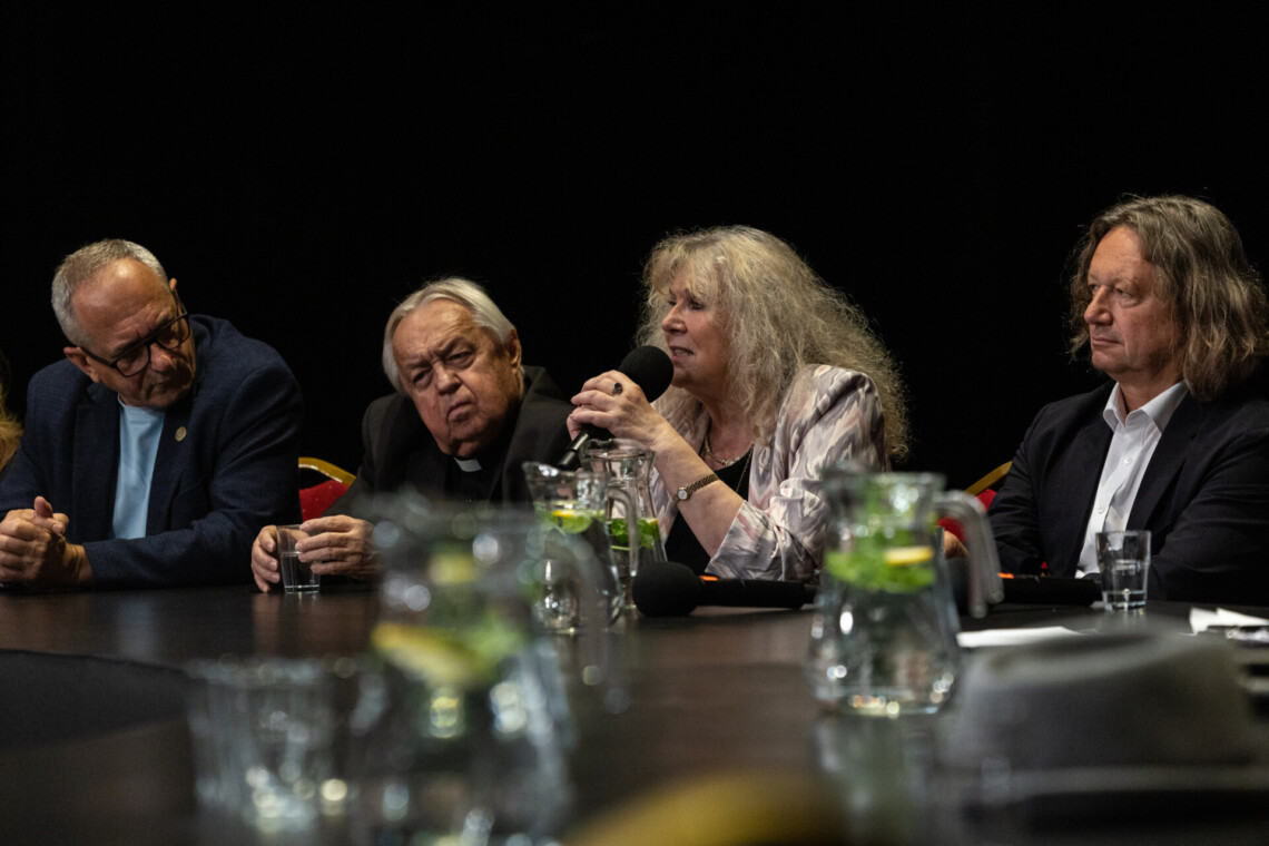 Krystyna Doktorowicz przemawiająca do mikrofonu siedząc za stołem