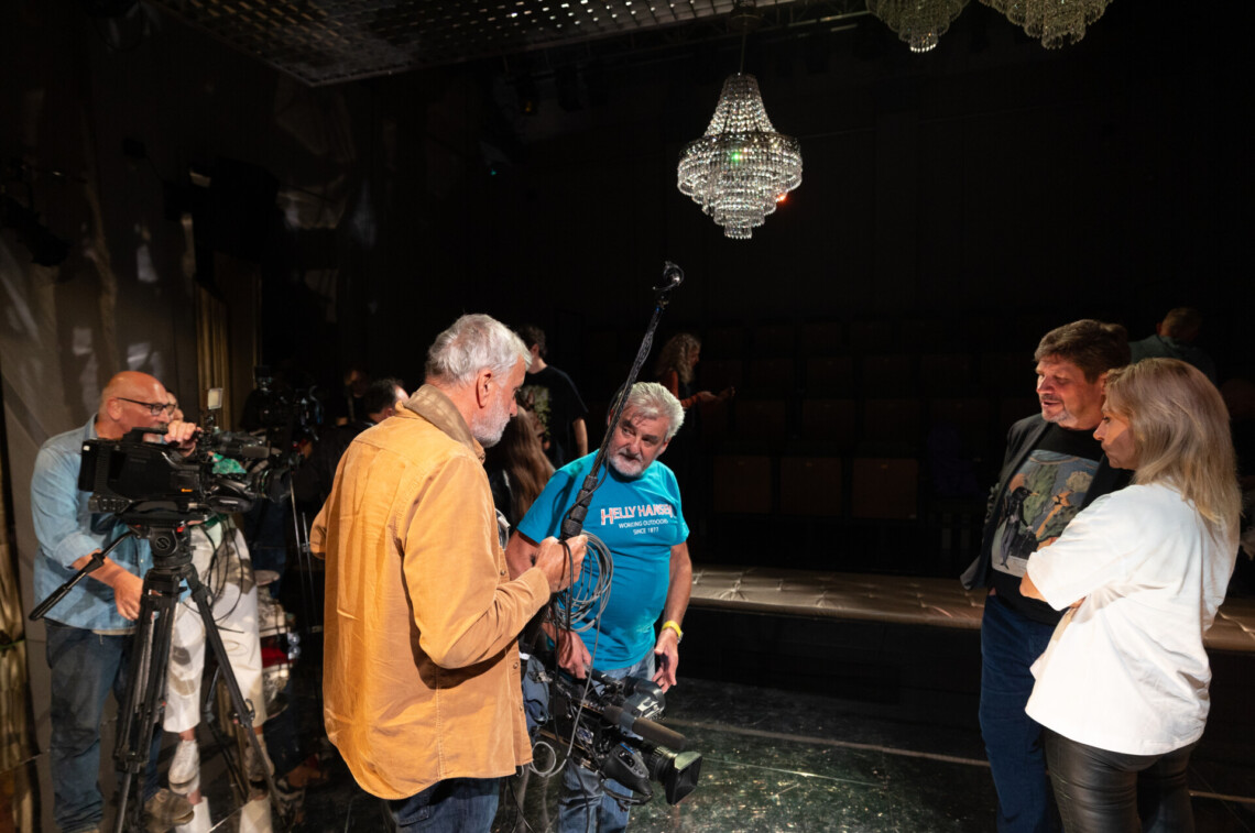 Po prawej stronie dziennikarka przeprowadza wywiad z Dyrektorem Robertem Talarczykiem. Po lewej stronie operatorzy kamer.