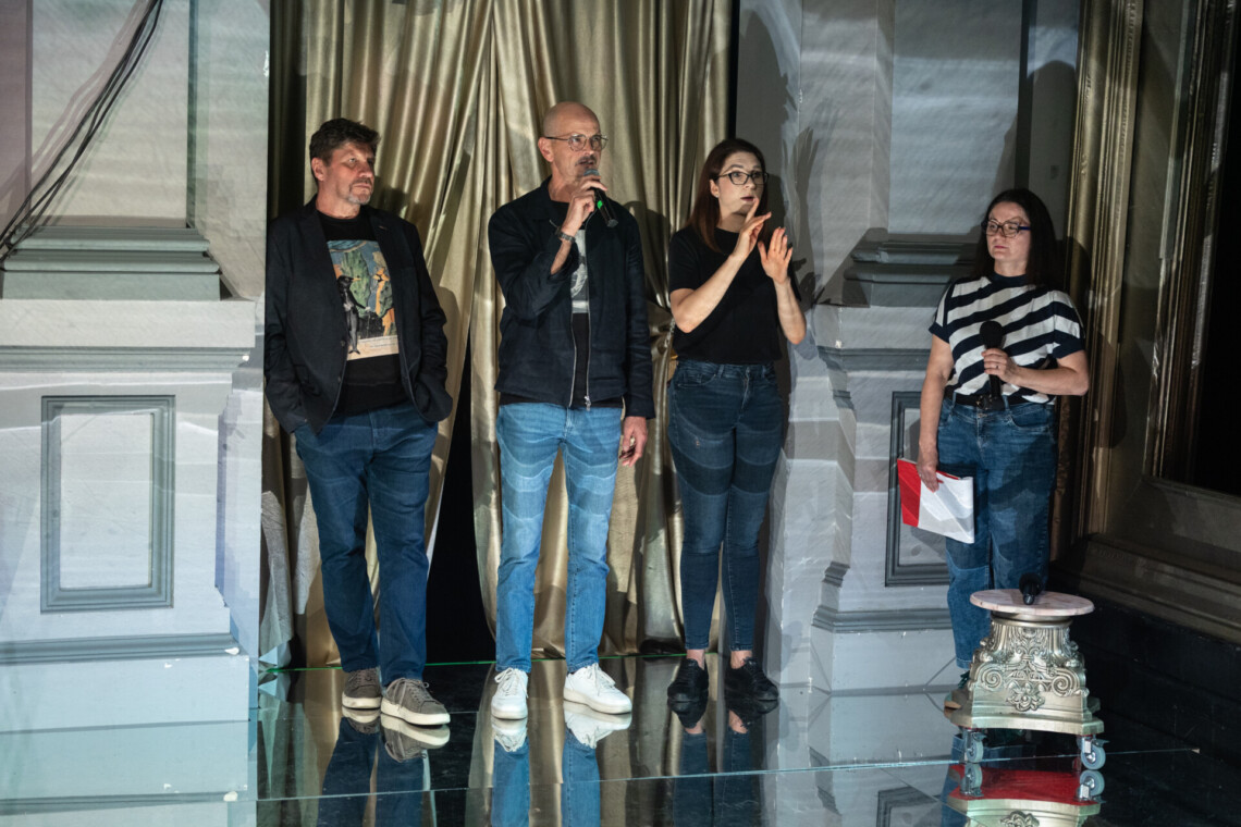 Na pierwszym planie od lewej Dyrektor Robert Talarczyk, Dyrektor Bogusław Jasiok przemawiający do mikrofonu, Tłumaczka PJM w trakcie pracy. Za nimi złota kotara. Na drugim planie Rzeczniczka prasowa teatru.