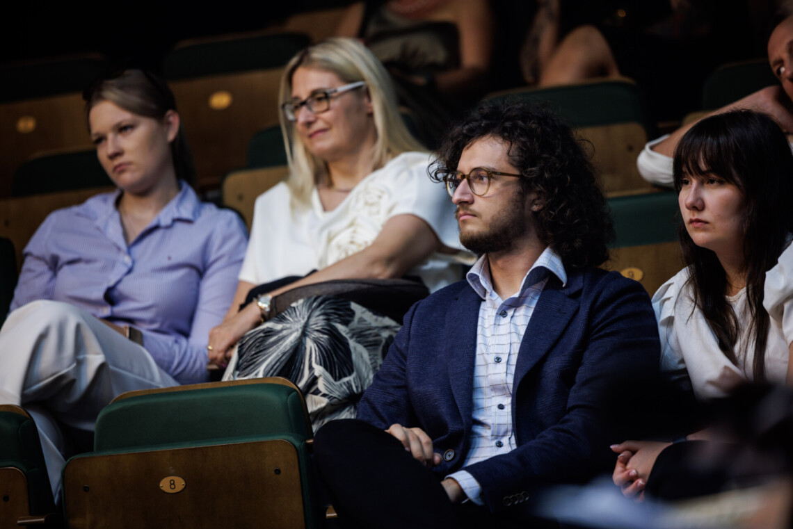 Osoby siedzące na widowni, przybliżenie na cztery osoby siedzące w dwóch rzędach