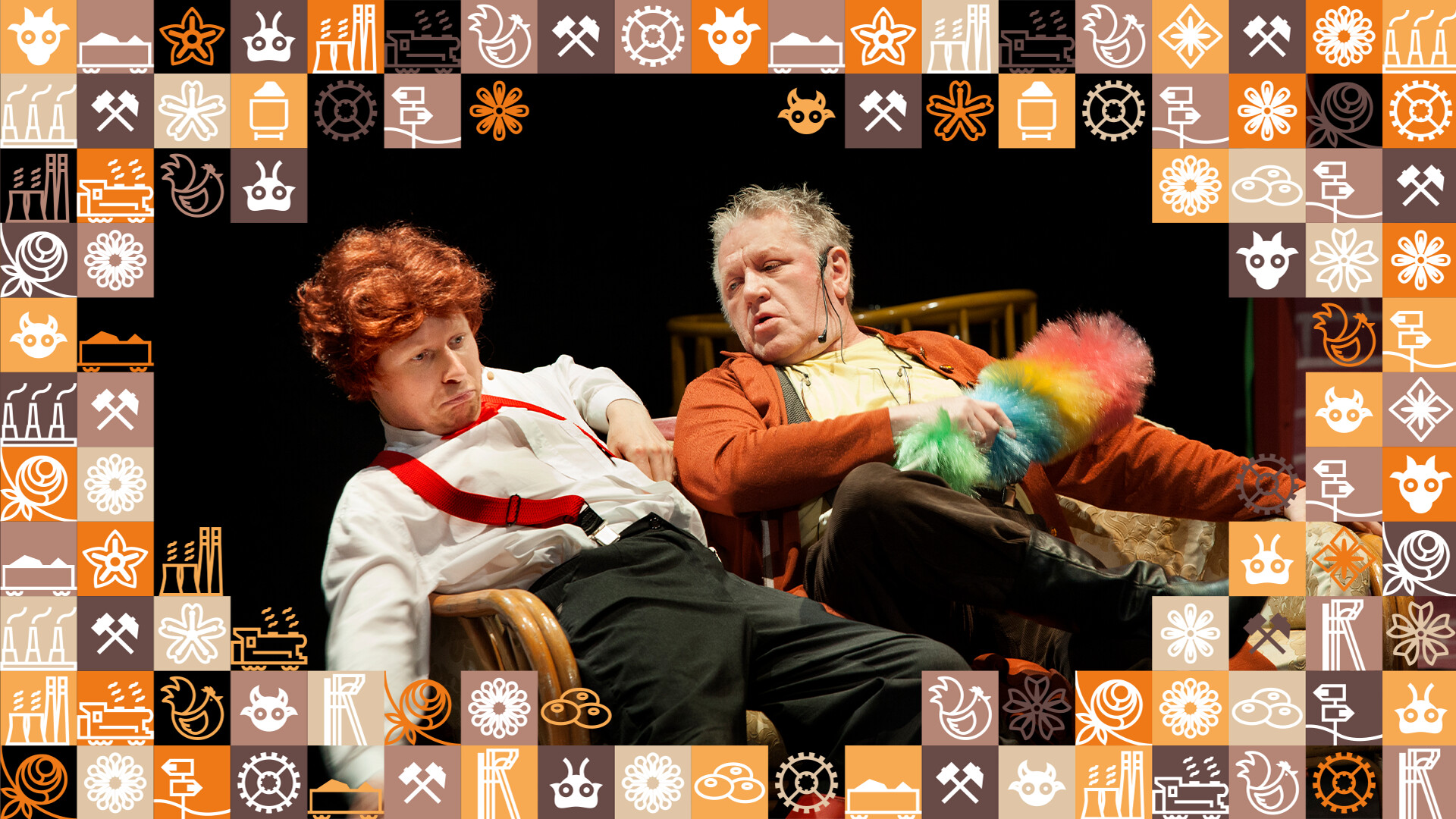 Mężczyźni siedzący obok siebie, z lewej rudy mężczyzna półleży, mężczyzna obok trzyma w dłoniach kolorową miotełkę do kurzu; wokół zdjęcia ramka z małych kwadracików w różnych kolorach (odcienie pomarańczowego i brązowego) przedstawiające obrazki związane ze Śląskiem, np. szyb górniczy, wagon z węglem, kluski śląskie