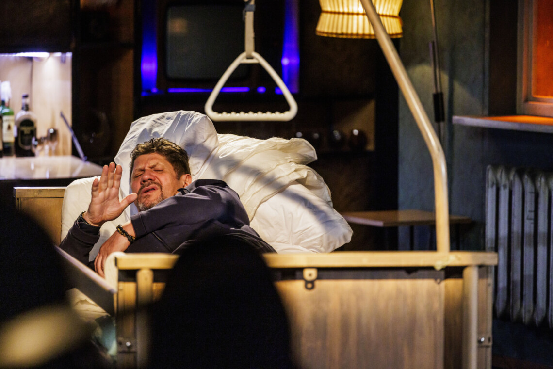 Mężczyzna leżący w ubraniu w rehabilitacyjnym łóżku z białą pościelą