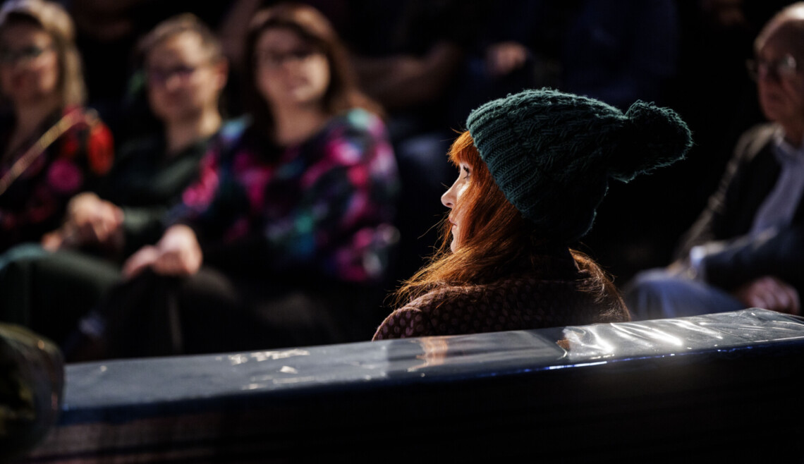 Kobieta w czapce z pontonem siedzi, ujęcie od tyłu pod kątem