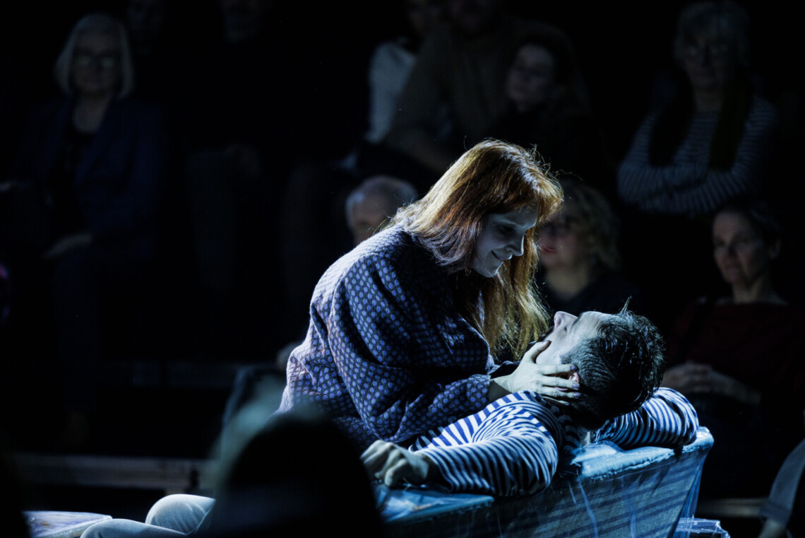 Kobieta siedząca na mężczyźnie, patrzą sobie w twarz, kobieta opiera dłonie na jego twarzy