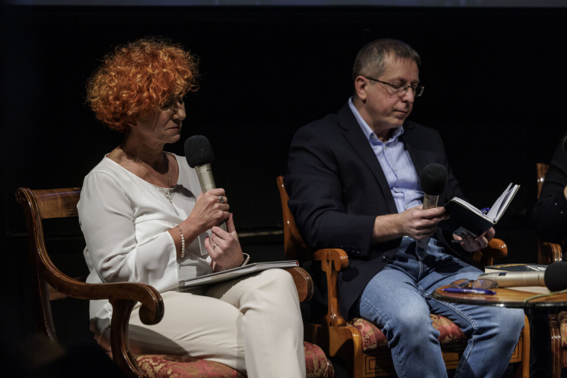 Na krzesłach siedzą autorzy - Judyta Watoła i Dariusz Kortko, kobieta trzyma przed sobą mikrofon, mężczyzna przegląda notatnik