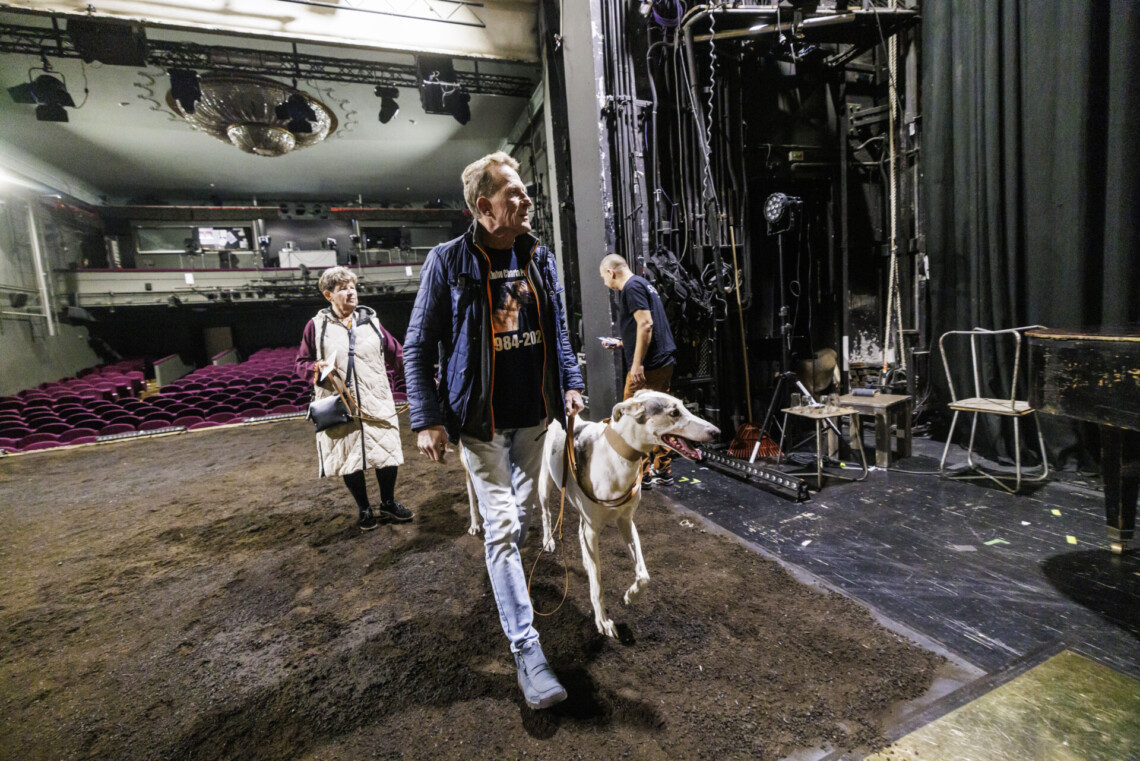 Mężczyzna z białym hartem przechadzający się po scenie, w tle pusta widownia