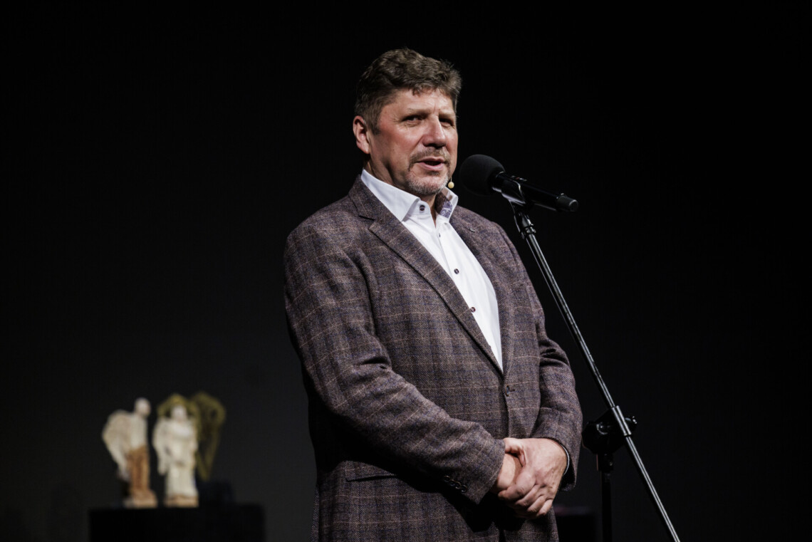 Dyrektor Robert Talarczyk przemawia do mikrofony stojącego na statywie. W tle statuetki Angelus Kulis.