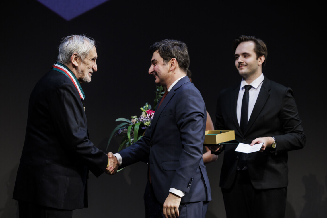 Wojewoda Marek Wójcik ściska dłoń Jerzego Głybin. Za nimi stoi bileter trzymający w dłoniach odznaczenie.