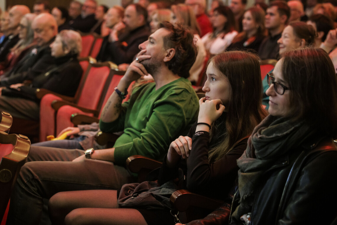 Publiczność siedząca na widowni, widok z boku.