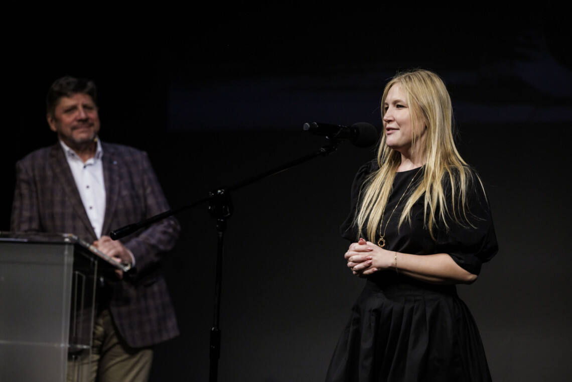 Na pierwszym planie Joanna Bojczuk członkini Zarządu Województwa Śląskiego przemawia do mikrofonu stojącego na statywie. Na drugim planie Dyrektor Robert Talarczyk stoi oparty o mównicę.