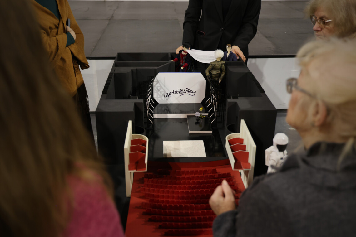 Osoby stojące wokół makiety Dużej Sceny Teatru Śląskiego ze scenografią spektaklu Wujek.81. Czarna ballada, ujęcie od góry