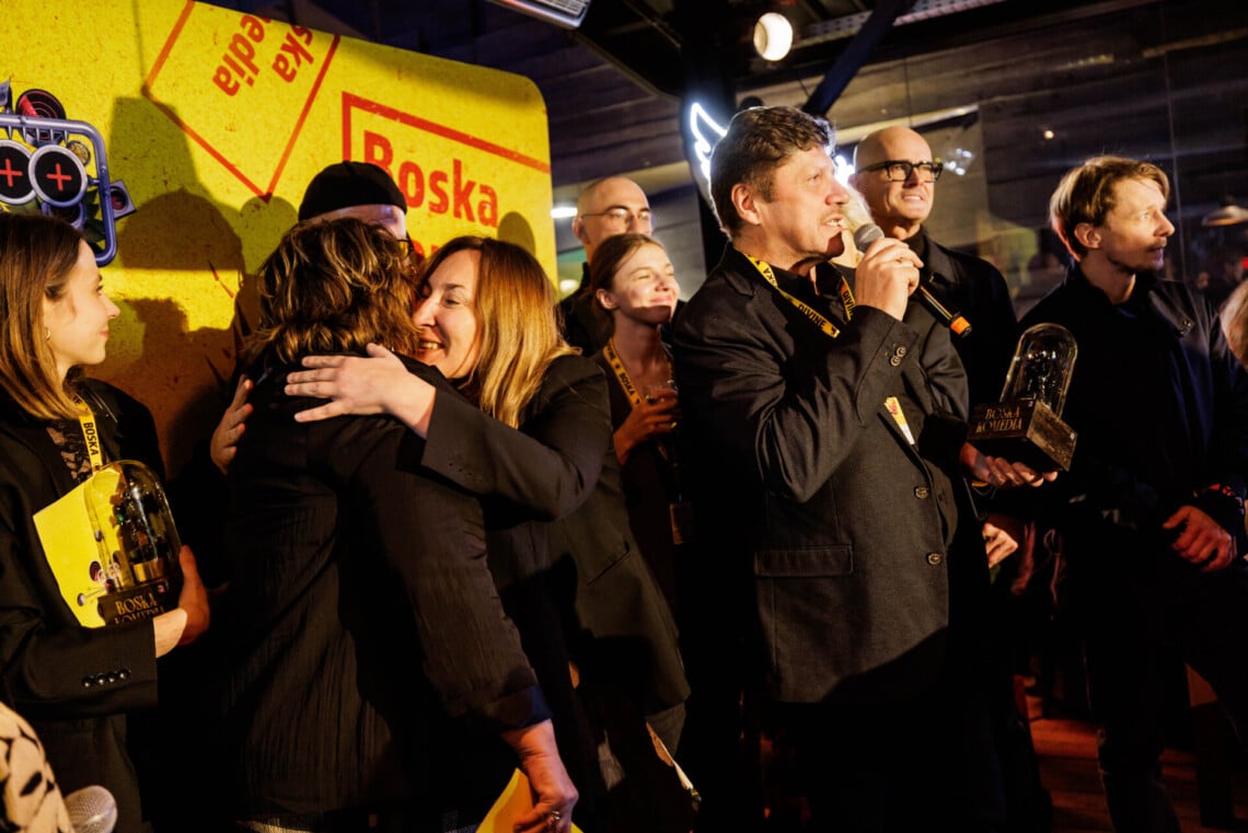 Grupa ludzi z Teatru stojących razem, dyrektor Robert Talarczyk przemawia do mikrofonu, obok Maja Kleczewska i Grażyna Bułka ściskają się