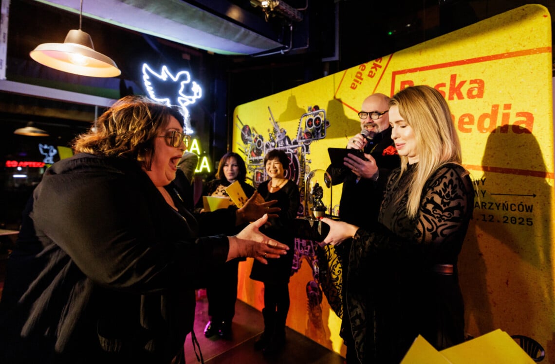 Grażyna Bułka odbiera nagrodę, ma wyciągnięte ręce do przodu w trakcie sięgania po nagrodę, szeroko otwarte usta, ujęcie z boku